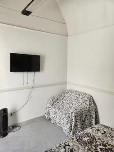 een witte kamer met een bed en een flatscreen-tv bij Notti al Vesuvio in Boscoreale
