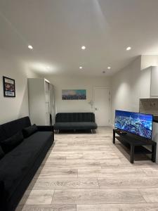 a living room with two black couches and a flat screen tv at Modern flat in Victoria in London