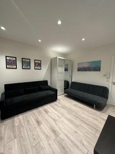 a living room with two black couches and a wooden floor at Modern flat in Victoria in London