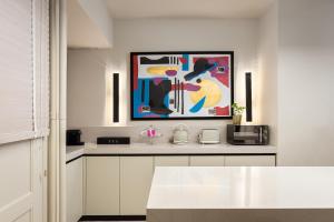 a kitchen with white cabinets and a painting on the wall at Anaktora Luxury Apartment at Kolonaki in Athens