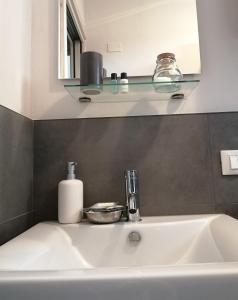 a white sink in a bathroom with a shelf above it at Stanze Ildesco in Bergamo