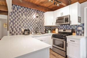 a kitchen with white cabinets and a stove and microwave at Ursa Minor- Modern Resort Chalet- Hot Tub in Big Bear Lake