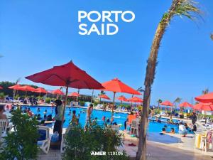 un gruppo di persone in una piscina con ombrelloni rossi di Port Said city, Damietta Port Said coastal road num2996 a Port Said