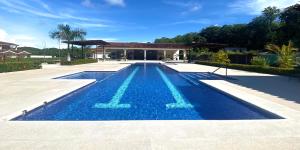 a swimming pool with blue water in front of a house at Jacarandas #16, 5 min tamarindo in Villarreal