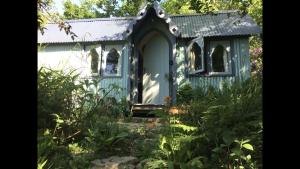 a blue shed in the middle of a garden at Magical Tabernacle in a Beautiful Setting with Hot Tub in Bude