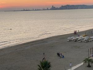 - une plage avec des personnes et des parasols au coucher du soleil dans l'établissement Wave Beachfront Apartments, à Durrës