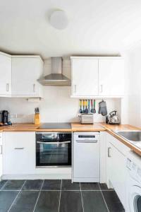 a kitchen with white cabinets and a stove top oven at Quiet 2 bed flat in SW London Parking Inc in Teddington