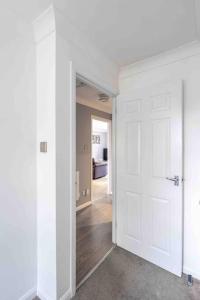 une chambre vide avec une porte blanche et un couloir dans l'établissement Quiet 2 bed flat in SW London Parking Inc, à Teddington