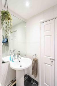 La salle de bains blanche est pourvue d'un lavabo et d'une douche. dans l'établissement Quiet 2 bed flat in SW London Parking Inc, à Teddington
