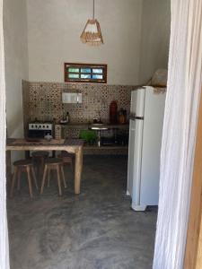 a kitchen with a table and a white refrigerator at Recanto da Alice in Trancoso