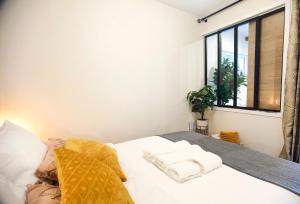 a bedroom with a bed with white sheets and a window at Exquisite tiny house with garden and air con - between Paris-Disneyland - 3mins from train station in Noisy-le-Grand