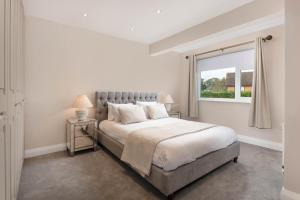 a white bedroom with a large bed and a window at Air Host and Stay - Formby station sanctuary sleeps 9, parking, 2 bath in Formby