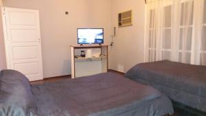 um quarto com duas camas e uma televisão e uma porta em HOSTAL HOUSE REYMON,habitaciones privadas" precio por persona" em Mendoza