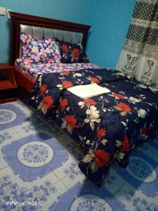 a bedroom with a bed with a floral bedspread at EDISON CITY PALACE GUEST HOME in Bertoua