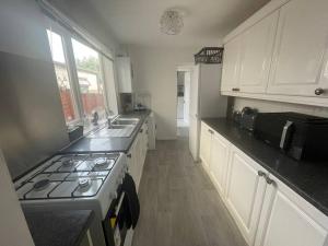 a kitchen with white cabinets and a stove top oven at 3 Bedroom House in Dartford in Kent