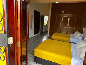 sypialnia z 2 łóżkami z żółtą i białą pościelą w obiekcie Casa Marin Framboyan w mieście Oaxaca