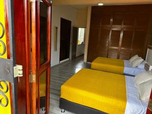 a bedroom with two beds with yellow and white sheets at Casa Marin Framboyan in Oaxaca City +4 photos