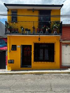 a yellow building with chairs on a balcony at Casa Marin Framboyan in Oaxaca City
