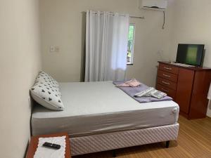 Dormitorio pequeño con cama y TV en Omi Haus, en Pomerode