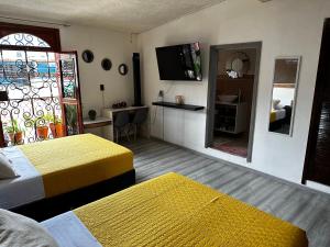 a hotel room with two beds and a television at Casa Marin Framboyan in Oaxaca City