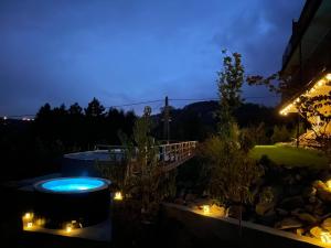 a backyard at night with a hot tub and lights at apartamentwroznowiepl in Rożnów