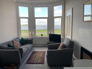 a living room with two couches and a large window at Seaview one bedroom apartment in centre of Largs in Largs