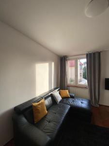 a black leather couch in a living room with a window at Apartament Celna in Nysa