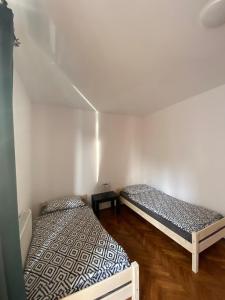 two beds in a room with white walls and wooden floors at Apartament Celna in Nysa