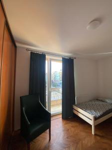 a bedroom with a bed and a window and a chair at Apartament Celna in Nysa