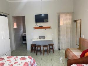 阿瓜斯－迪聖佩德羅的住宿－CANTINHO DA PAZ!，一间设有一张桌子、凳子和墙上的电视的房间