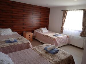 um quarto com três camas e uma janela em Hostal JC em Puerto Natales