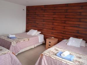 a bedroom with two beds and a wooden wall at Hostal JC in Puerto Natales