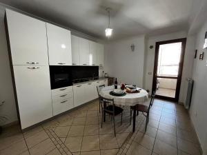 una cocina con armarios blancos y una mesa con sillas. en Appartamento Anastasia, en Monteroni di Lecce