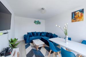 ein Wohnzimmer mit einem blauen Sofa und einem Tisch in der Unterkunft Perle Parisienne, Vue Captivante in Saint-Ouen
