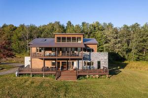 a large house with a large deck in a field at Stone Ledge in Margaretville