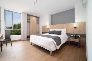 a bedroom with a bed and a desk and a window at Hotel Plaza del Lili in Cali