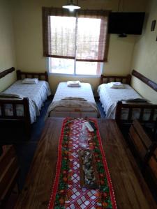 a room with three beds and a table in it at cabañas altos de giardino in Villa Giardino