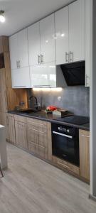 a kitchen with white cabinets and a black dishwasher at Apartament Pod Klonem in Bartoszyce