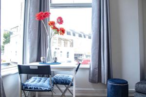 una mesa con un jarrón con flores en una ventana en Central Dover Apartment 1, en Kent