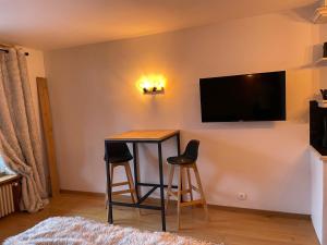 a room with a table and two stools and a television on a wall at Studio du cerf in Megève