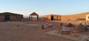 een woestijn met gebouwen en tafels in het zand bij Chegaga Regency Camp in El Gouera