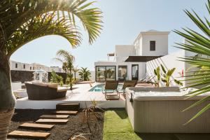 un patio trasero con piscina y una casa en Villa Faro, en Playa Blanca