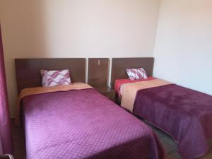 two beds in a room with purple blankets at El Molino Lodging/Restaurant in Torotoro