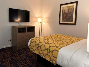 a hotel room with a bed and a flat screen tv at Baymont by Wyndham Indianapolis Northwest in Indianapolis