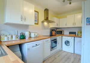 a kitchen with white appliances and white cabinets at Rainbow Cottage in Thorpeness