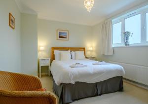 a bedroom with a large bed and a chair at Rainbow Cottage in Thorpeness