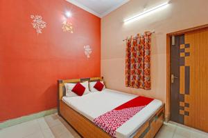 een kleine slaapkamer met een bed met rode muren bij OYO Flagship Darsh Residency in Dhanbad