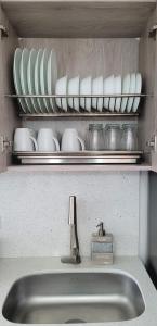 - un évier de cuisine avec des assiettes et des bols sur une étagère dans l'établissement Modern High-Rise 2/2 Apartment with City View., à Sabaneta