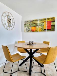 a dining room table with chairs and a clock at Modern High-Rise 2/2 Apartment with City View. in Sabaneta