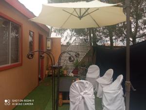 un groupe de chaises blanches sous un parapluie dans l'établissement Familiar Hostal, à Chillán